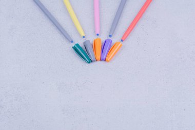 Gri arkaplanda beş tane çok renkli jel kalem var. Yüksek kalite fotoğraf