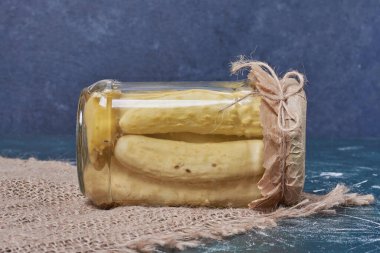 Mavi arka planda cam kavanozda yünlü masa örtüsü ile ev yapımı salatalık turşusu. Yüksek kalite fotoğraf