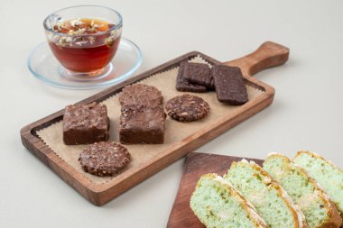 Çikolatalı bisküvi, şam fıstıklı kek dilimleri ve beyaz yüzeyde bir bardak çay. Yüksek kalite fotoğraf