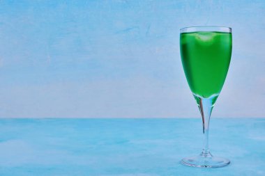 Mavi arka planda izole edilmiş bir bardak yeşil meyve suyu. Yüksek kalite fotoğraf