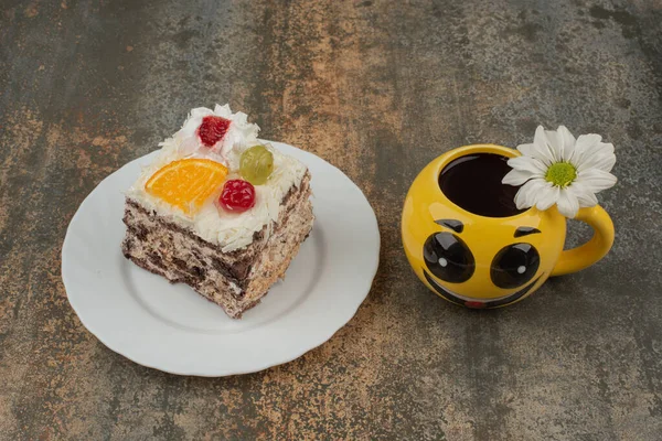 An emoji mug with sweet cake and chamomile on marble background