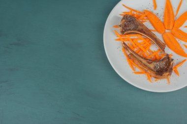 Beyaz tabakta kuzu pirzolası ve havuç dilimleri. Yüksek kalite fotoğraf