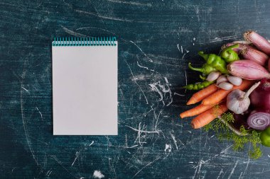 Sağ tarafta mavi arka planda izole edilmiş çeşitli sebzeler ve bir de yemek tarifi kitabı. Yüksek kalite fotoğraf