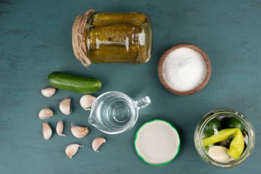 Cam kavanozda sebze turşusu ve mavi zemin üzerinde salatalık ve sarımsaklı tuz kasesi. Yüksek kalite fotoğraf