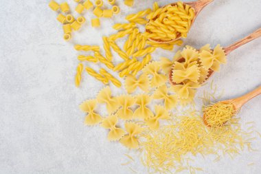 Beyaz arka planda pişmemiş taze makarna kaşıkları.