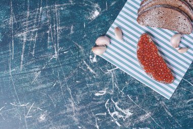 Mavi arka planda sarımsaklı siyah ekmek dilimleri ve kırmızı havyar. Yüksek kalite fotoğraf