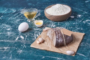 Sarımsaklı ekmek dilimleri ve mavi arka planda malzemeler. Yüksek kalite fotoğraf