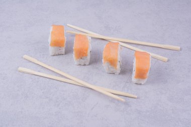 Gri arka planda ahşap çubuklarla somonlar yuvarlanıyor. Yüksek kalite fotoğraf