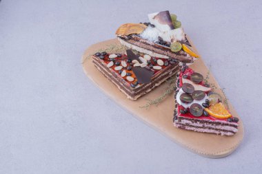 Çikolata, fındık ve meyvelerle ahşap tabakta üçgen şeklinde pasta dilimleri. Yüksek kalite fotoğraf