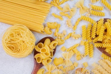  Beyaz arka planda çeşitli makarna şekilleri ve kaşıklar. Yüksek kalite fotoğraf