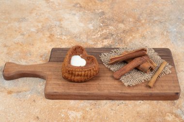 Tahtada kalp şeklinde kek ve tarçın çubukları var. Yüksek kalite fotoğraf