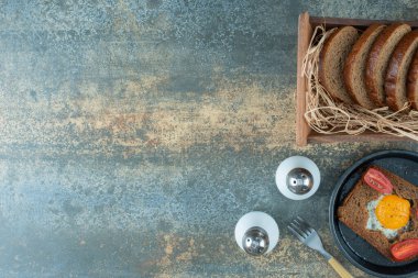 Koyu bir tava, kızarmış yumurta ve mermer zemin üzerinde kahverengi ekmek dilimleri. Yüksek kalite fotoğraf