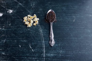 Mavi masada kuru siyah çay ve papatya çiçekleri. Yüksek kalite fotoğraf