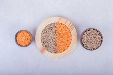 Tahta tabak ve kaselerde iki çeşit çiğ fasulye ve mercimek. Yüksek kalite fotoğraf