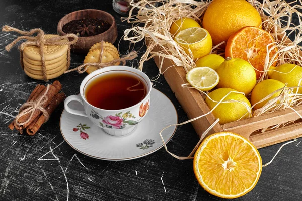A wooden tray of citrus fruits with a cup of tea. High quality photo