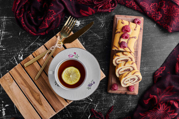 Roll cake with chocolate and berries and a cup of tea. High quality photo