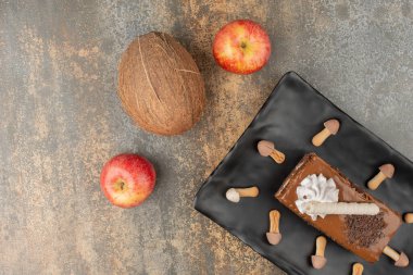 Bir dilim tatlı turta, iki kırmızı elma ve Hindistan cevizi mermer arka planda.