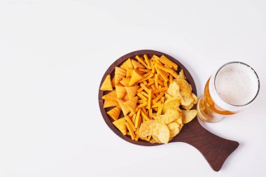 Beyaz arka planda cips ve abur cubur dolu bir bardak bira