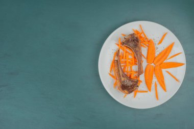 Beyaz tabakta kuzu pirzolası ve havuç dilimleri. Yüksek kalite fotoğraf