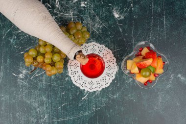 Bir şişe meyve suyu, üzüm ve bir tabak meyve. 