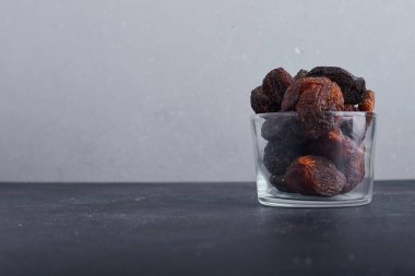 Gri arka planda cam bir fincanda kurumuş erikler. Yüksek kalite fotoğraf