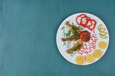 Otlar ve sebzelerle dolu beyaz bir tabakta tavuk bacağı. Yüksek kalite fotoğraf