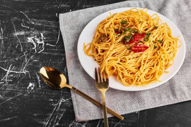 Beyaz tabakta sebzeli ve otlu spagetti.