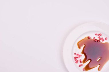 Nar tohumlarının ve beyaz tabakta sıvı sosun üst görüntüsü. Yüksek kalite fotoğraf