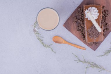 Tahta bir tabakta bir dilim karamel kek ve bir bardak latte. Yüksek kalite fotoğraf