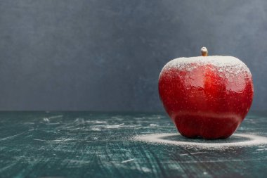 Mavi arka planda pudra ile süslenmiş kırmızı elma. Yüksek kalite fotoğraf