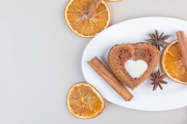 Kalp şeklinde pasta, portakal dilimleri ve beyaz tabakta tarçın. Yüksek kalite fotoğraf