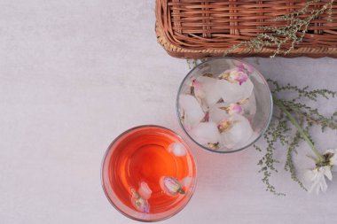 Beyaz yüzeyde bir bardak limonata ve buz küplerinde donmuş çiçekler. Yüksek kalite fotoğraf