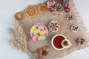 Çuval bezin üzerinde bir fincan lezzetli çayla tatlı şekerler. Yüksek kalite fotoğraf