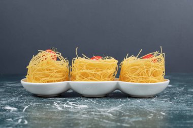 Beyaz tabakta domatesli çiğ spagetti yuvaları. Yüksek kalite fotoğraf