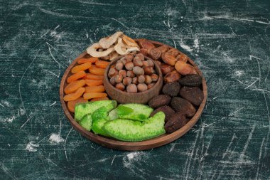 Kurumuş meyveli ahşap tabak mermer arka planda. 