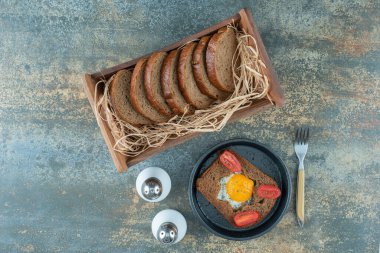 Koyu bir tava, kızarmış yumurta ve mermer zemin üzerinde kahverengi ekmek dilimleri. Yüksek kalite fotoğraf