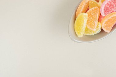 Bej yüzeyde kasede tatlı renkli marmelatlar. Yüksek kalite fotoğraf