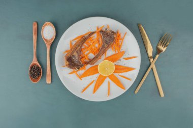 Beyaz tabakta kuzu pirzolası ve havuç dilimleri. Yüksek kalite fotoğraf