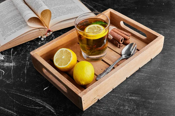 Yellow lemons isolated on black background with a glass of drink in a wooden tray. High quality photo