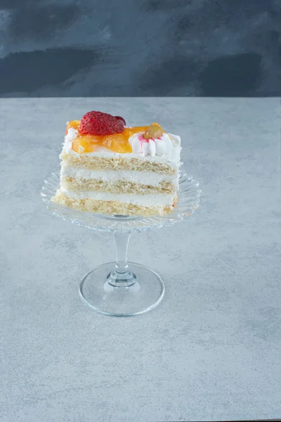 Delicious piece of cake on glass plate on marble background