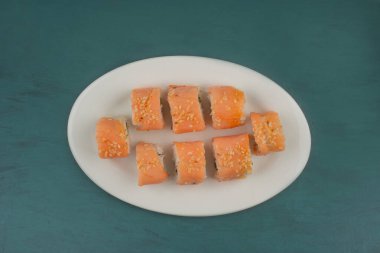 Philadelphia suşi böreği, beyaz tabakta susam tohumlarıyla süslenmiş. Yüksek kalite fotoğraf