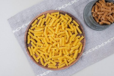 Çiğ spiral makarnayı fincanda, tabağı masa örtüsünde. Yüksek kalite fotoğraf