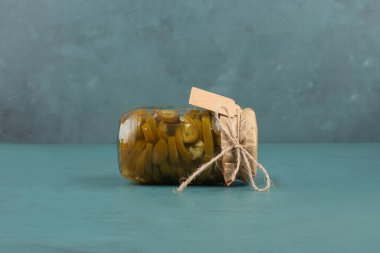 Bir kavanoz yeşil biber turşusu ve mavi masada resim çerçevesi. Yüksek kalite fotoğraf