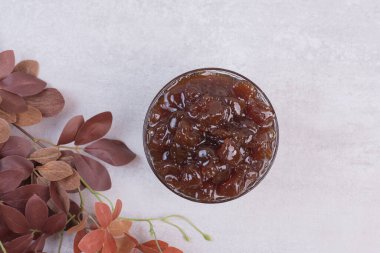 Reçelli bir bardak ve beyaz arka planda yaprakları olan bir dal. Yüksek kalite fotoğraf