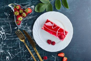 Beyaz tabakta ahududu şurubuyla peynirli kek dilimi. Yüksek kalite fotoğraf