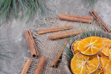 Tahta bir fincanda turuncu dilimler ve etrafında tarçın çubukları var. Yüksek kalite fotoğraf