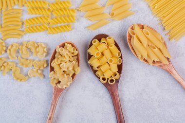  Beyaz arka planda çeşitli makarna şekilleri ve kaşıklar. Yüksek kalite fotoğraf