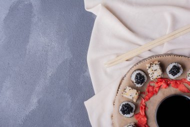 Suşi seti. Maki ve alaska suşisi masa örtüsü, zencefil turşusu ve soya sosuyla ahşap tabakta yuvarlanıyor. Yüksek kalite fotoğraf