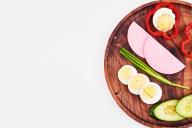 Haşlanmış yumurta, kırmızı biber, sosis, yeşil soğan ve ahşap tabakta salatalık. Yüksek kalite fotoğraf