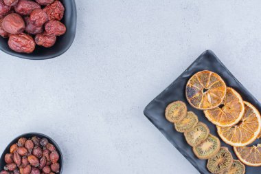 Kurutulmuş gül kalçası, gümüş çilek, kivi ve mermer yüzeyde portakallar. Yüksek kalite fotoğraf